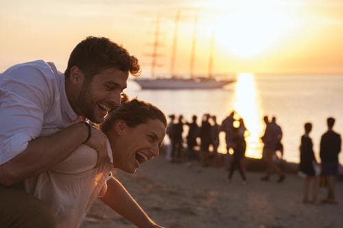couple_enjoying_sunset_at_beach_in_mykonos_greece-medium