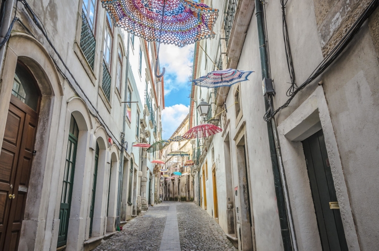 Sombrillas colgadas en una calle angosta en Coimbra